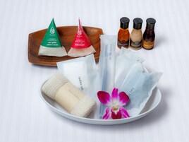 Una bandeja con diversos productos de baño, incluyendo sales de baño verdes y rojas, un cepillo corporal y jabón de baño.