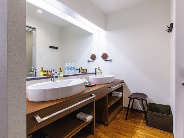 Un baño moderno con dos lavamanos, un espejo grande y un mueble de tocador de madera.