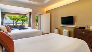 Habitación de hotel con dos camas, televisión, escritorio y vista a la playa.