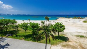 Una playa con aguas turquesas cristalinas, una orilla de arena y vegetación verde.