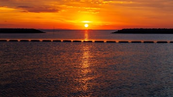 A sunset over a calm body of water with a pier extending into the water.
