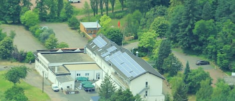 A building with a flat roof, solar panels, and a parking area with several cars.