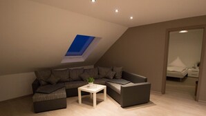 A modern living room with a sectional sofa, a small white table, and a skylight. - Hotel Restaurant Litermont (Nalbach)