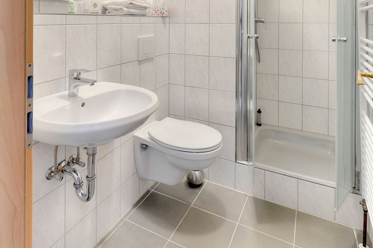 Ein modernes Badezimmer mit Waschbecken, Toilette und einer Duschkabine.