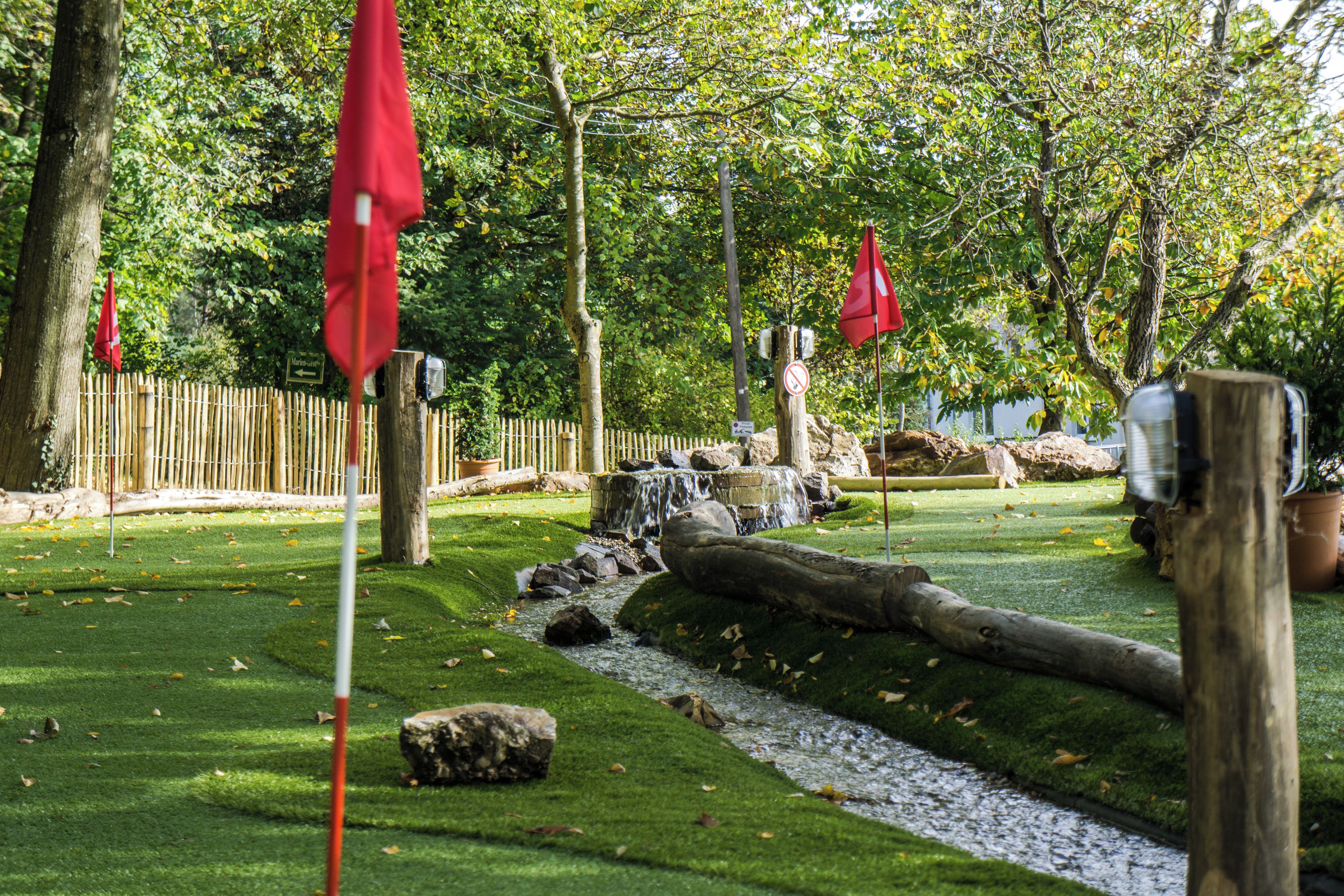 A garden with a small stream, wooden fence, and red flags.