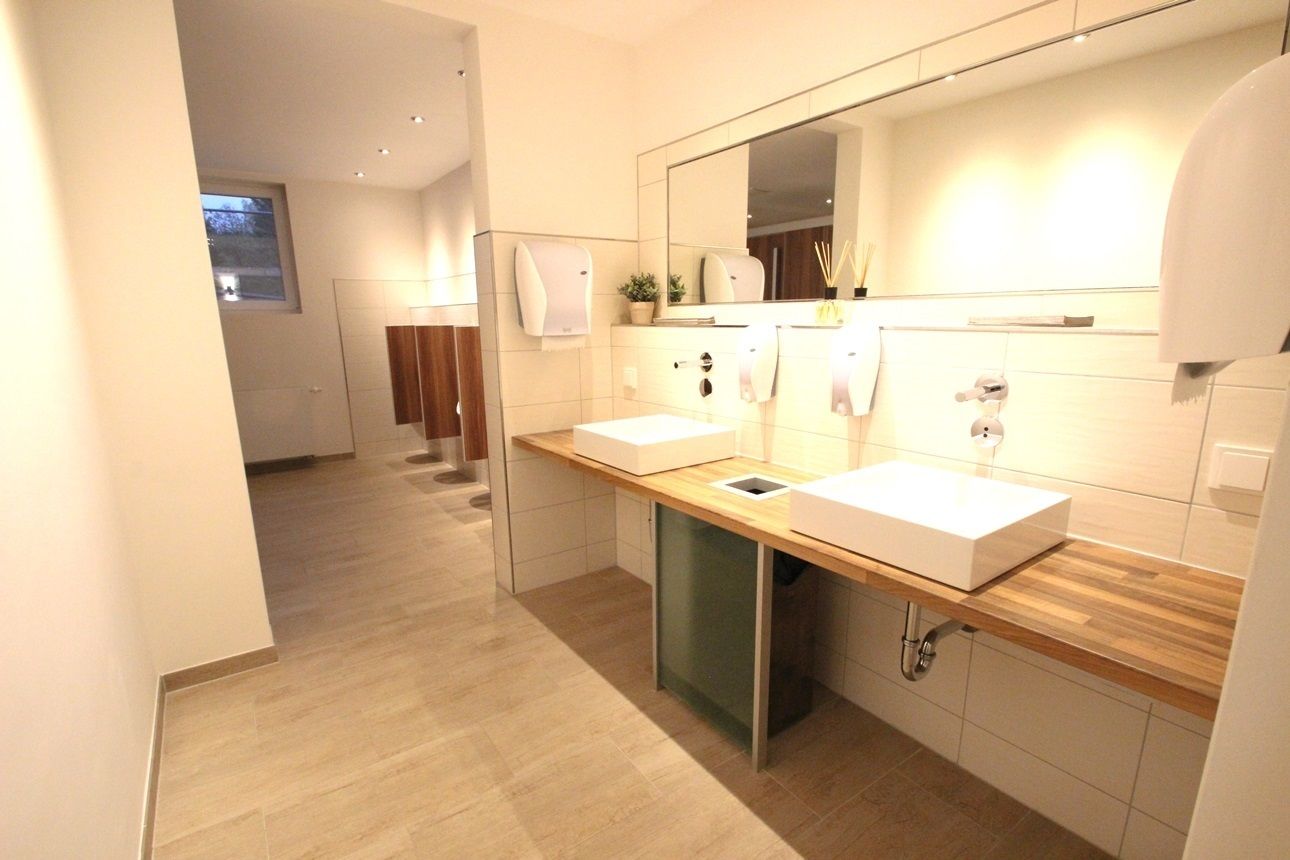 Ein modernes Badezimmer mit zwei Waschbecken, einem großen Spiegel und einer Holzauskleidung.