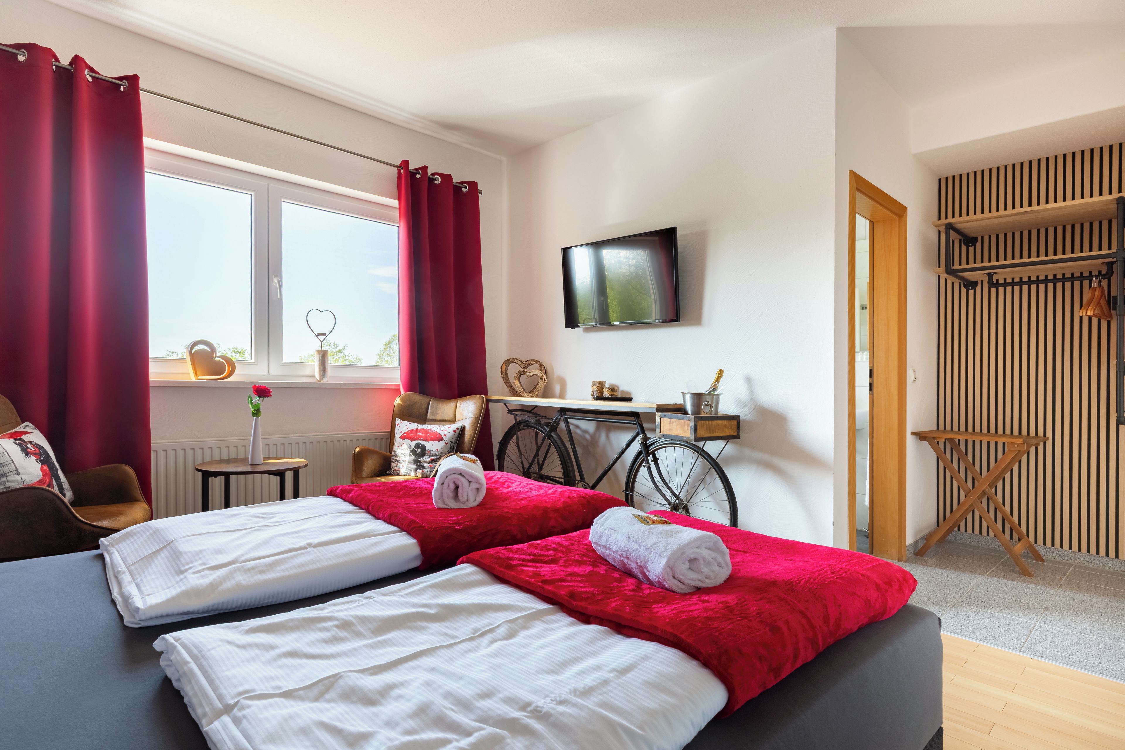 A hotel room with two beds, a TV, a bicycle, and a wooden wall panel.