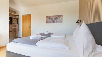 Habitación de hotel con cama, puerta de madera, cuadro colgado en la pared y lámpara de noche.