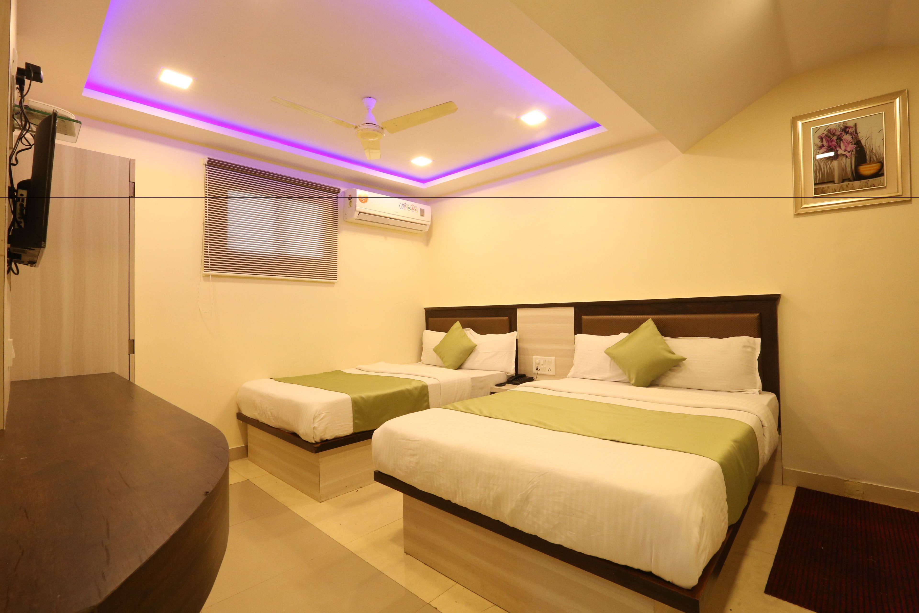 A hotel room with two beds, a ceiling fan, an air conditioning unit, and a framed picture on the wall.