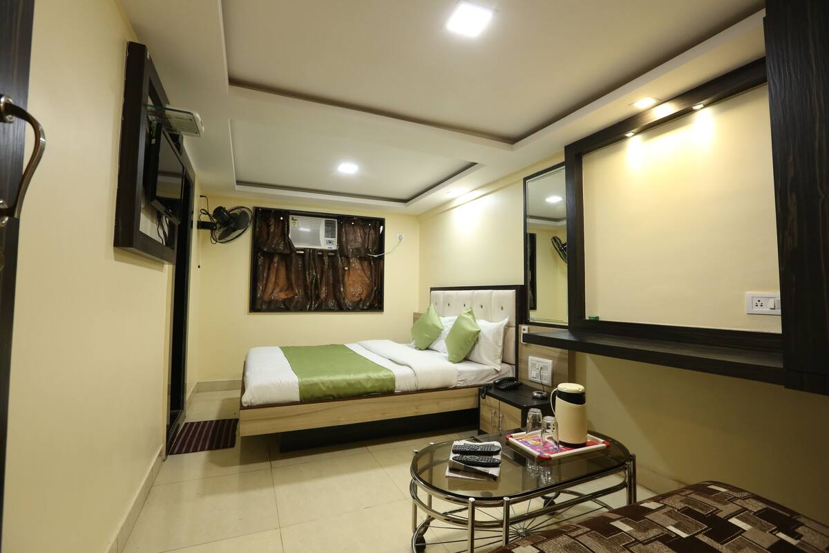 Quarto de hotel com cama, mesa de cabeceira e espelho.