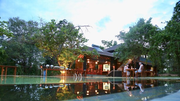 A lakeside restaurant with outdoor seating, a reflection pool, and a traditional building with a sloped roof. - Pinthaliya Resort & Spa (Avudangawa)