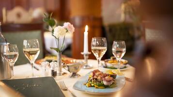 Une table à manger dressée avec des verres à vin, une bougie et un menu.