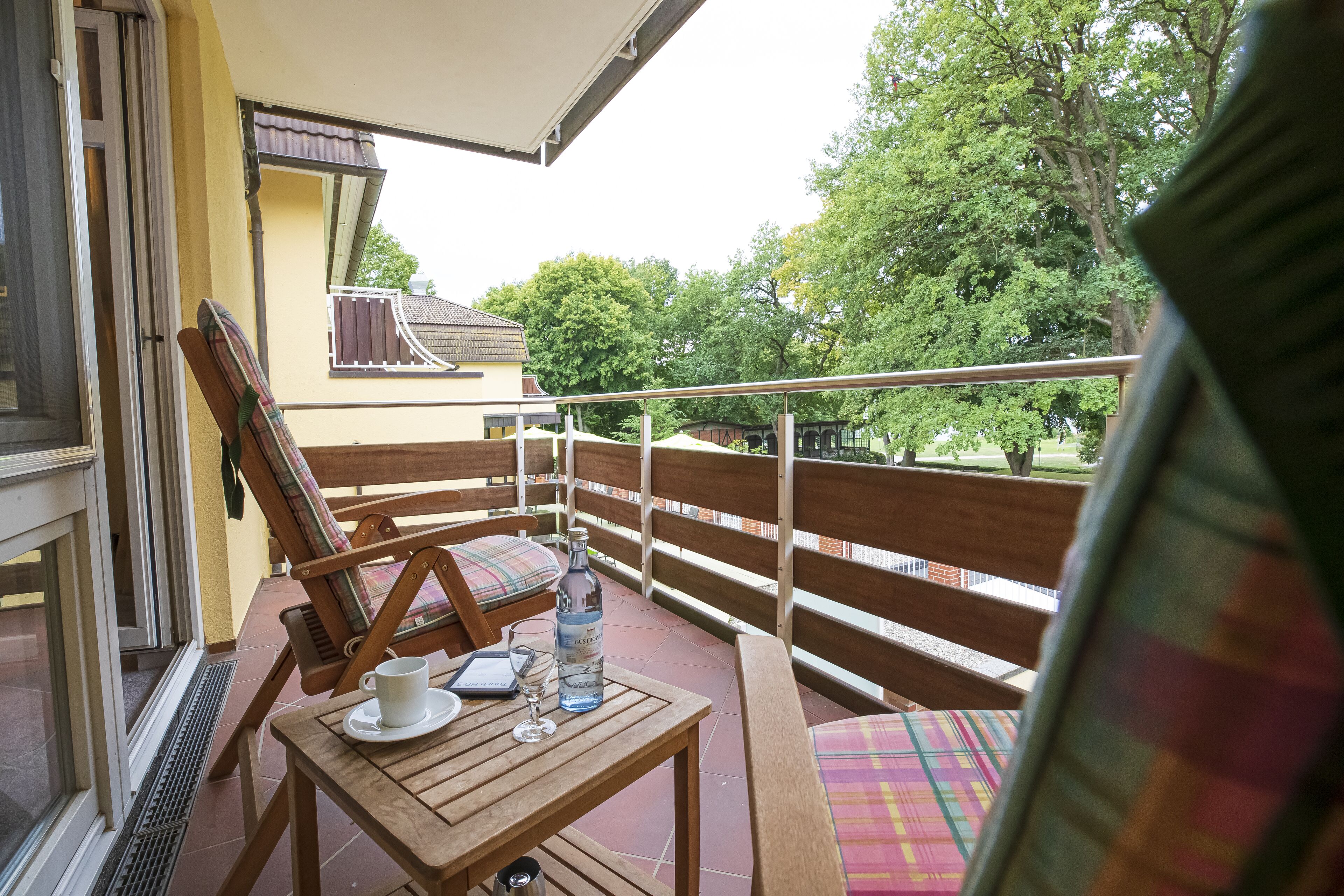 Ein Balkon mit einem Holztisch, einem Stuhl und einer Wasserflasche.