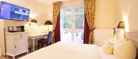 A hotel room with a bed, desk, chair, TV, and curtains.