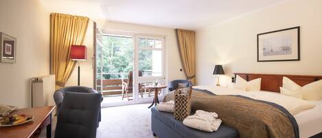 A hotel room with a bed, a desk, a chair, a table, and a view of the outdoors.