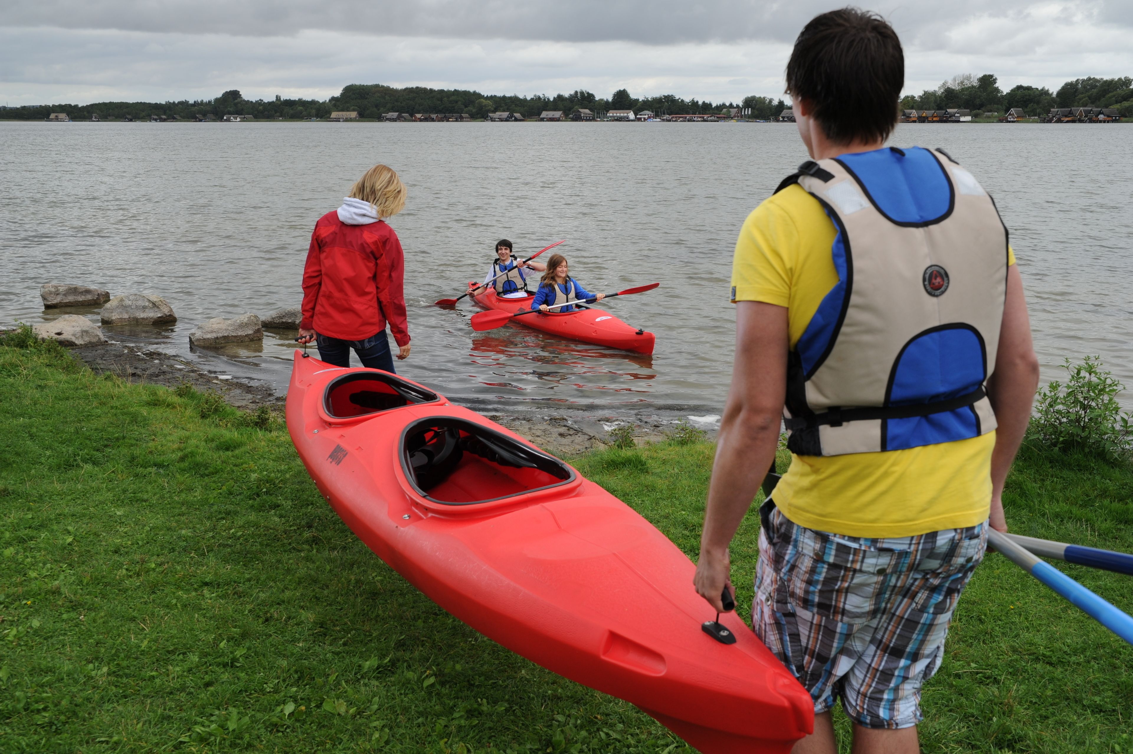 Un grupo de personas cerca del agua con kayaks y una pala.