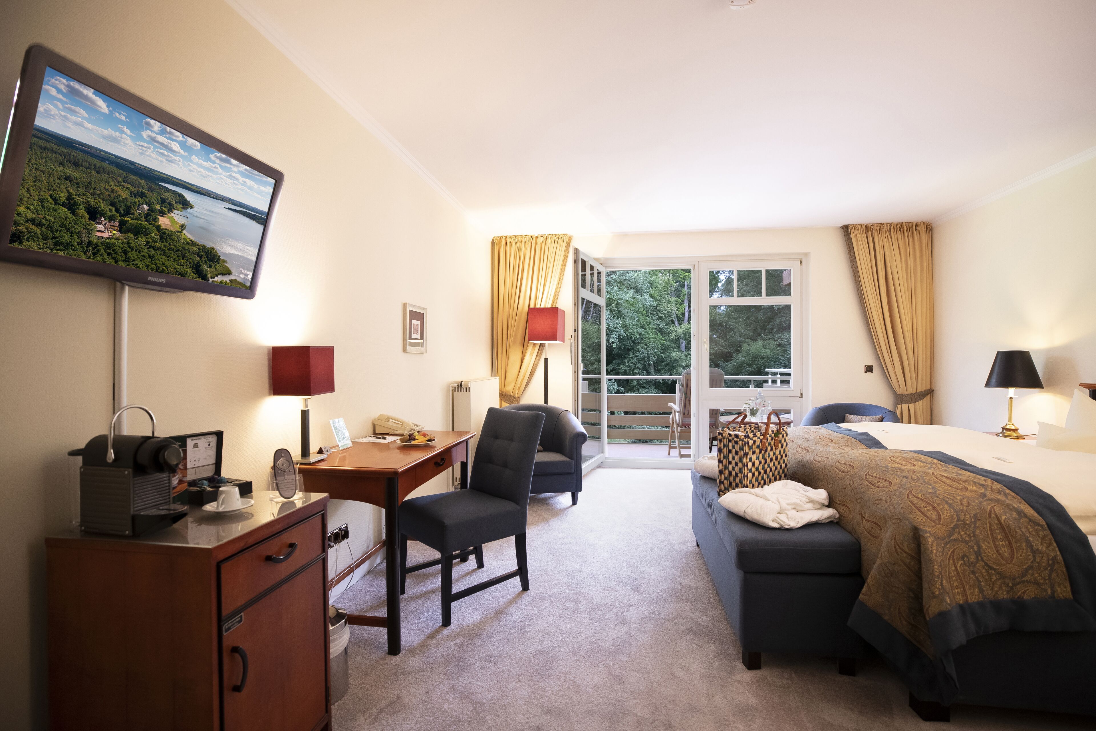 Une chambre d’hôtel équipée d’une télévision, d’un bureau, d’une chaise, d’un lit et offrant une vue sur l’extérieur par la fenêtre.