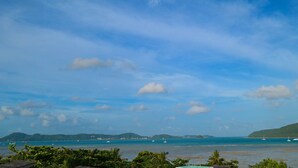 A coastal view with boats, greenery, and distant hills. - Almali Luxury Residence (Rawai)