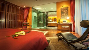 A hotel room with a large bed, a sitting area, a desk with a laptop, and a shower area. - Almali Luxury Residence (Rawai)