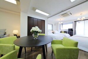 Une chambre d’hôtel avec un lit, un bureau, une chaise, une table ornée d’un vase de fleurs et une fenêtre avec des rideaux.