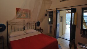 Un dormitorio con cama, mesita de noche, cortinas en la ventana, puerta que da al exterior y aire acondicionado instalado en la pared.