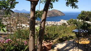 Un patio con mesa y silla, con vista a un pueblo costero y al mar.