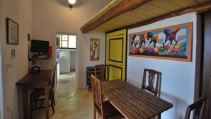 Un comedor con mobiliario de madera, una puerta amarilla y un mural colorido en la pared.
