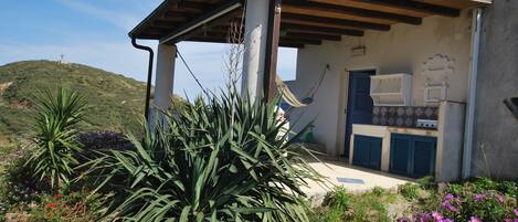A building with a covered patio, a door, and a small outdoor kitchen area.