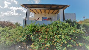 Un bâtiment doté d’une pergola en bois, d’un hamac et d’une porte bleue.