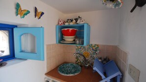 Une cuisine avec un meuble bleu, un évier et une fenêtre dotée d’un cadre bleu.