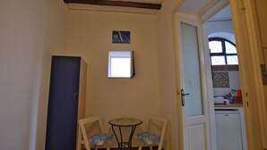 A small room with a table and two chairs, a door, and a window. - Capperino Mono (Lipari)