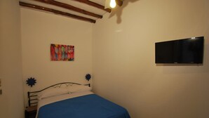 A bedroom with a bed, a flat-screen TV mounted on the wall, and a colorful artwork above the bed. - Capperino Mono (Lipari)