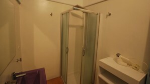 A bathroom with a glass shower enclosure, a white sink, and a towel rack. - Pomice Studio (Lipari)