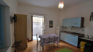 A compact kitchen with a dining table, a small island, and light blue cabinets. - Pomice Studio (Lipari)