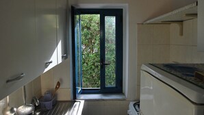 A compact kitchen with a window, a sink, a stove, and a dishwasher. - Villino Vulcano (Lipari)