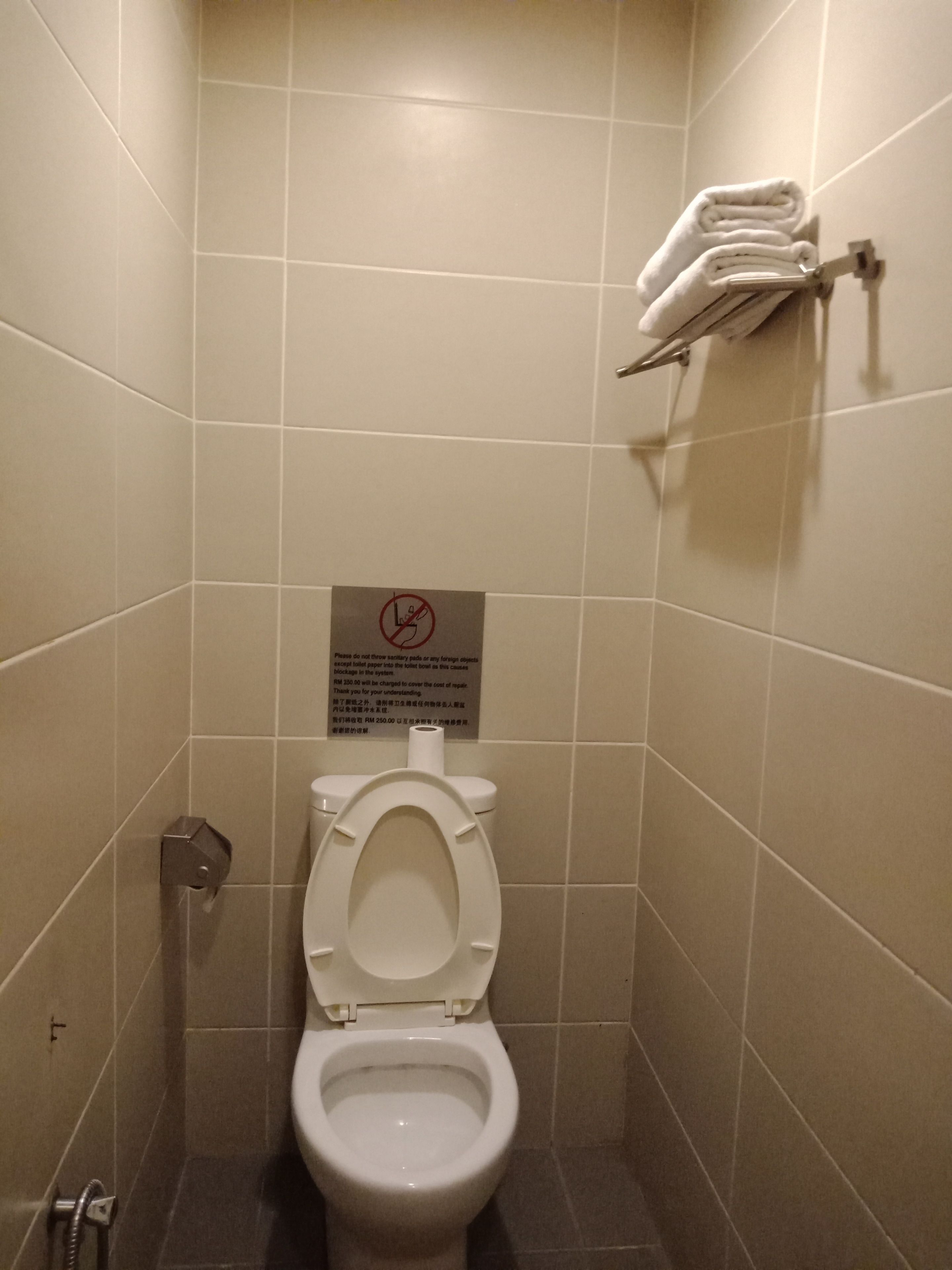 A small, clean bathroom with a toilet, a hand dryer, and a towel rack.