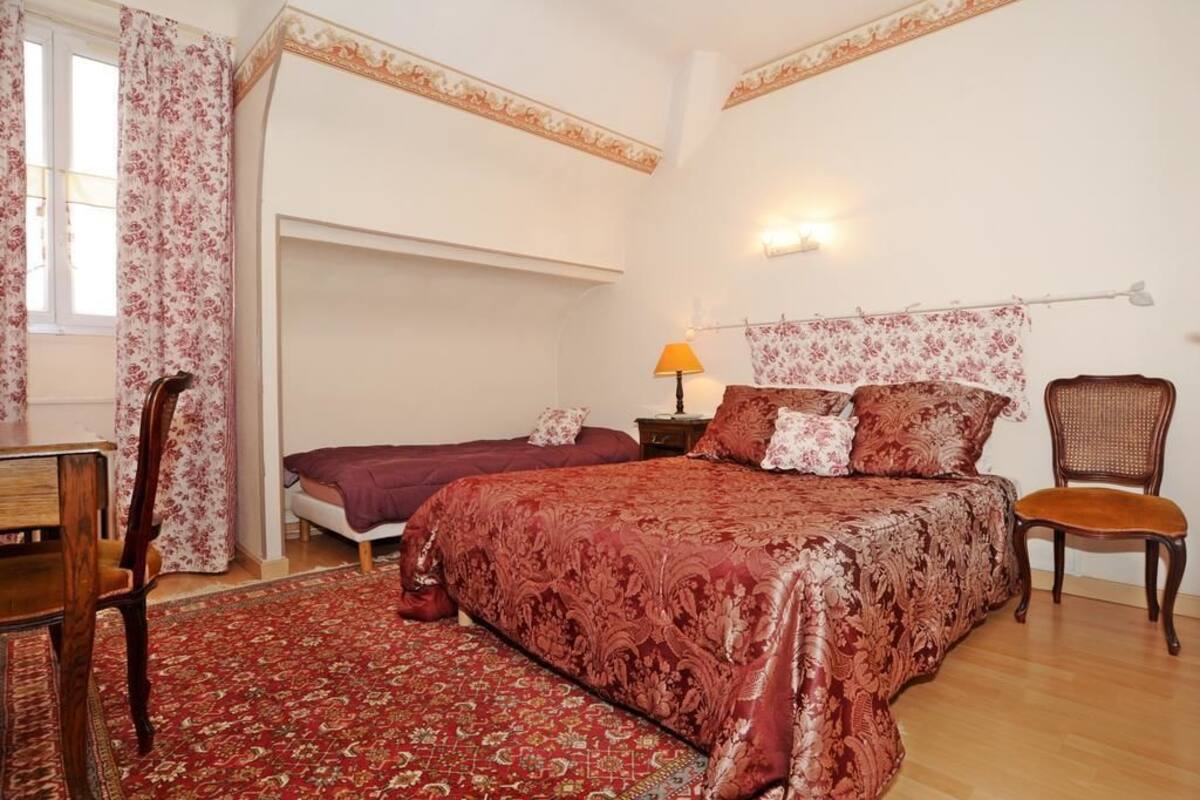 A bedroom with a large bed, a smaller bed, a desk, and a chair.