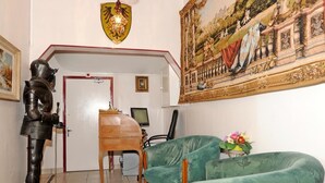 A room with a medieval knight statue, a wooden desk, a computer, and a green armchair. - Hôtel la Tour (Sully-sur-Loire)