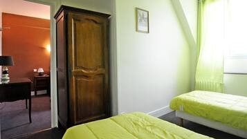 Une chambre avec deux lits, une armoire en bois, un bureau avec une lampe et un tableau encadré au mur.