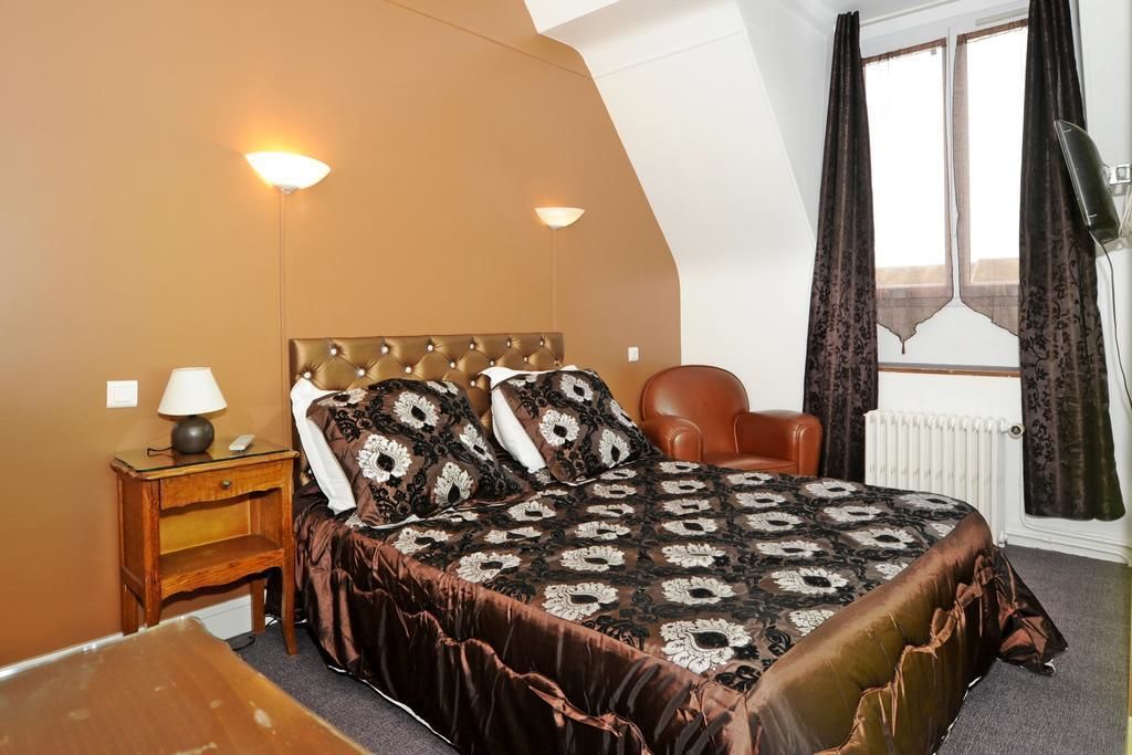 A bedroom with a large bed, a nightstand, a chair, and a window with curtains.