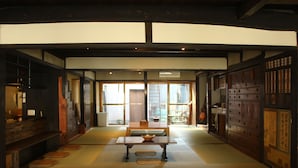 Een traditionele Japanse kamer met tatami vloeren, een lage tafel met een schaal, schuifdeuren en uitzicht op buiten.