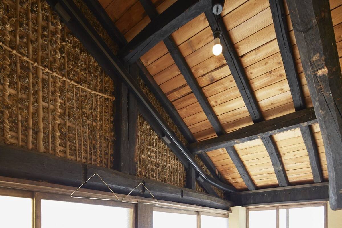 Une chambre avec un plafond en bois, un lit avec une literie blanche et de grandes fenêtres.