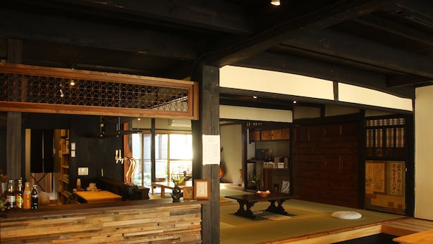 Een traditionele Japanse kamer met tatami vloerbedekking, een laag houten receptiebalie en een schuifdeur met kalligrafie.