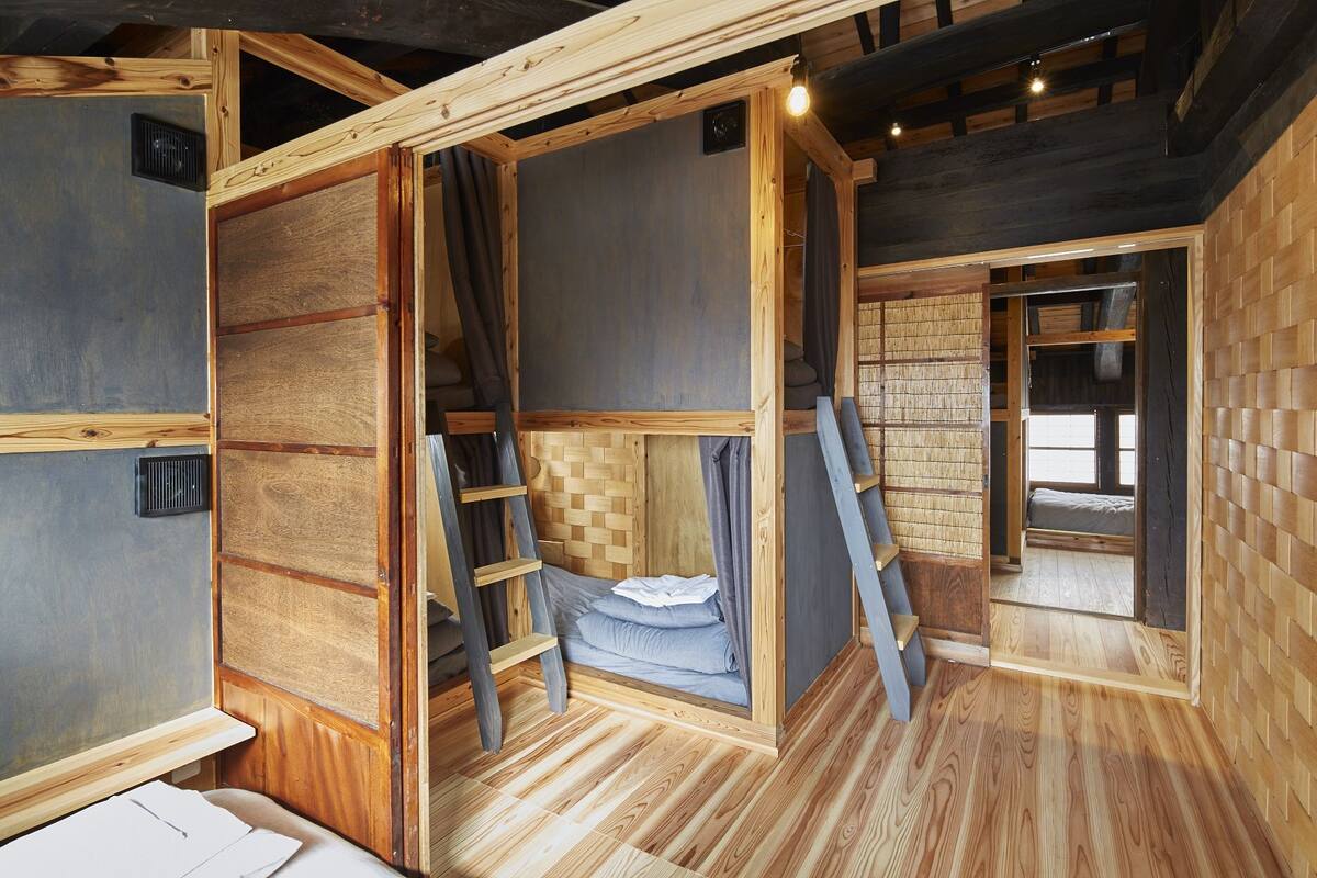 Une petite cabane en bois à plusieurs niveaux, dotée d’un lit en mezzanine, d’une échelle et d’un petit coin salon.