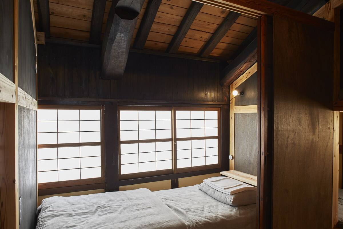 Une pièce de style japonais traditionnel, avec un sol recouvert de tatamis, un lit bas en bois et une porte coulissante.