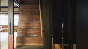 Een houten trap die leidt naar een donkere kamer met een geweven plafond.