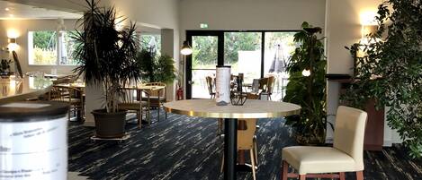 Un interior moderno con mesas redondas, sillas y plantas en macetas.