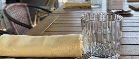 A wooden table with a glass, a napkin, and cutlery.