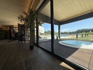 A modern indoor pool area with a view of a residential neighborhood and a clear sky. - Artémis Hôtel & Spa Bistro Coquet (Cohade)