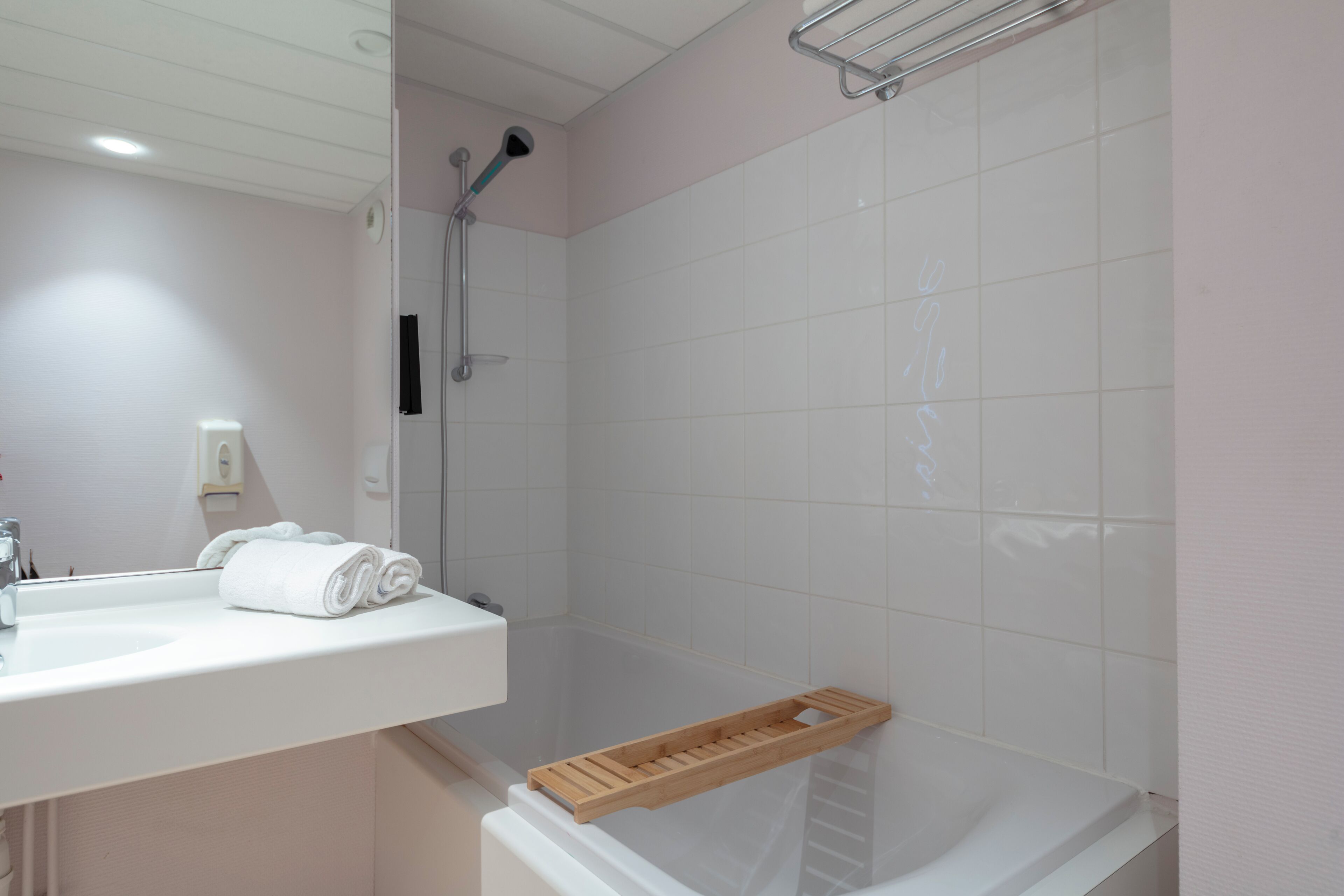A modern bathroom with a white sink, mirror, and shower.